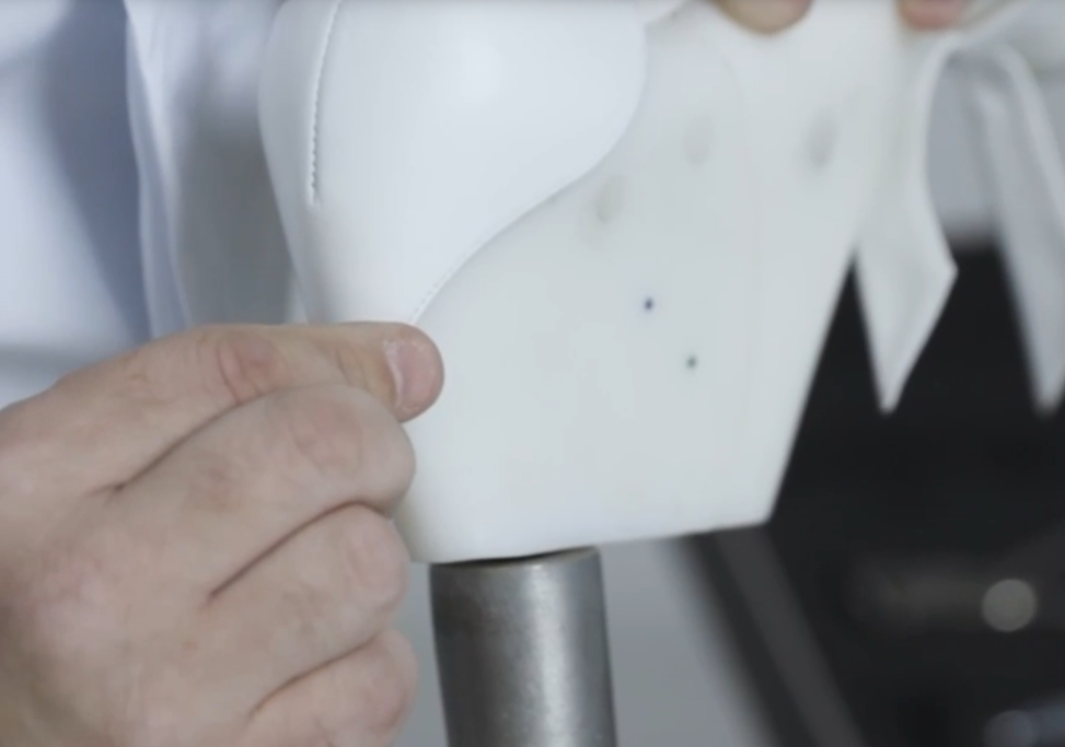 Artesão moldando o cabedal de um sapato na fôrma